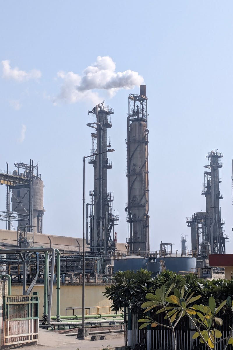 A detailed view of a chemical plant's tall chimneys and industrial structures against a clear sky.